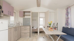 Una cocina compacta con electrodomésticos modernos, un comedor con mesa y sillas, y un rincón de descanso acogedor con sofá.