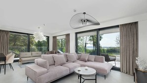 Una sala de estar moderna con un sofá seccional grande, una mesa de centro redonda y un comedor con una mesa y sillas.