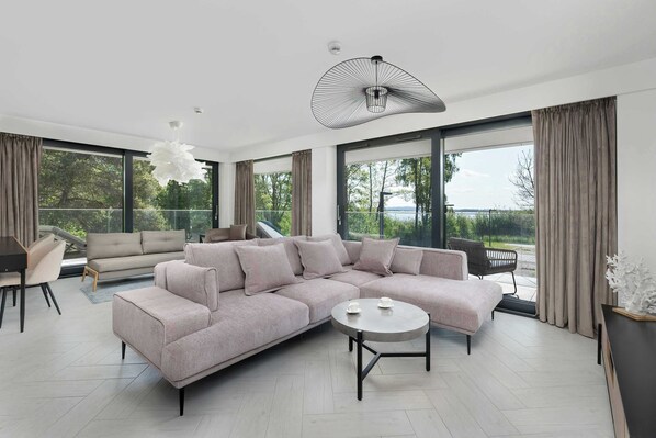 A modern living room with a large sectional sofa, a round coffee table, and a dining area with a table and chairs.