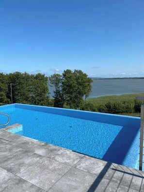 A rectangular swimming pool with clear blue water, surrounded by a tiled deck.