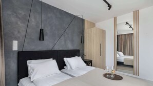 Un dormitorio moderno con una cama grande, dos mesitas de noche y un espejo que refleja un baño.