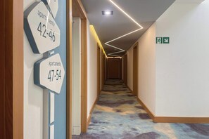 A hotel hallway with numbered apartment signs, a patterned carpet, and a modern light fixture. - Cozy Studio | Pool and Gym | Close to the Beach (Sarbinowo)