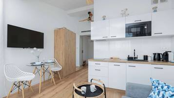 A modern kitchen with white cabinets, a Bosch oven, and a dining area with a glass table and white chairs.