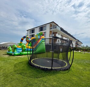 A residential building with a balcony, a trampoline, and an inflatable slide.