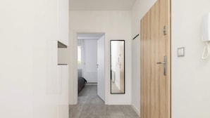 Un pasillo con una puerta de madera, un espejo y un teléfono en la pared.