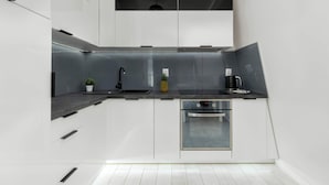 A modern kitchen with white cabinets, a stainless steel sink, and a built-in oven. - Functional Studio in Sopot | Parking | Close to the Beach (Sopot)