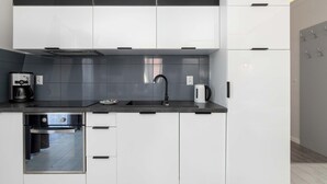 A modern kitchen with white cabinets, a black countertop, and a built-in oven.
