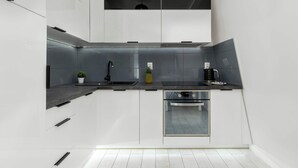 Una cocina moderna con armarios blancos, un lavamanos de acero inoxidable y un horno empotrado.