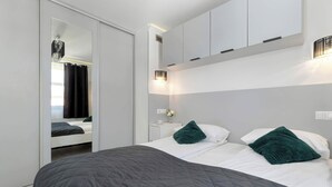 Un dormitorio moderno con cama, mesita de noche, espejo y armario empotrado.