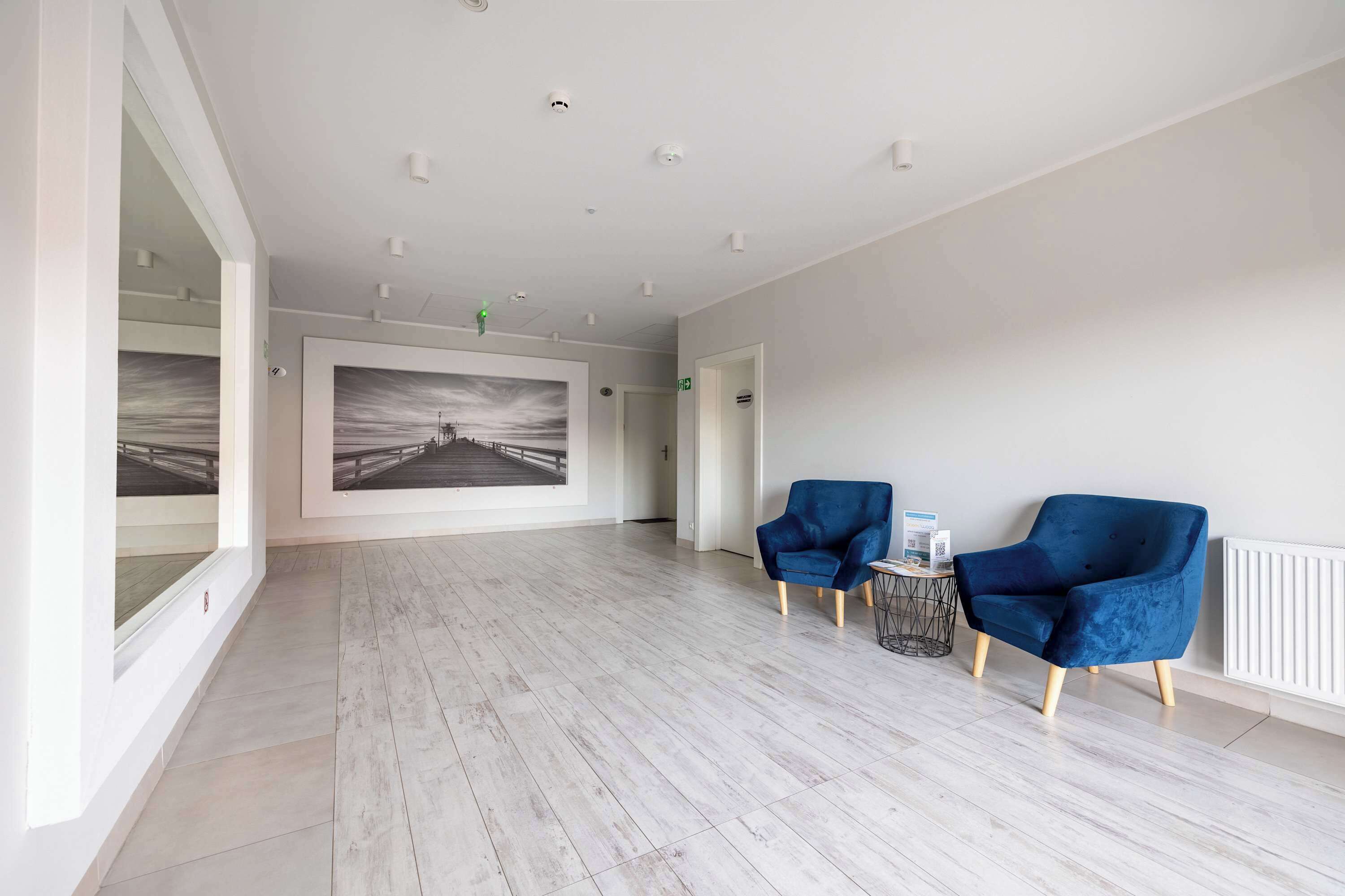 Un cuarto amplio con un ventanal grande, una fotografía en el marco en la pared y dos sillones azules.