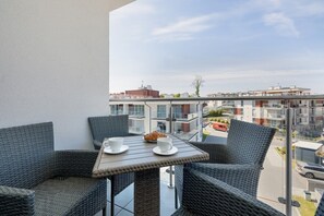 Un balcón con mobiliario de mimbre, una mesa y vistas a la ciudad.