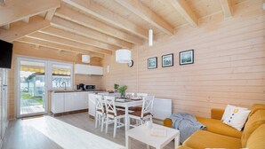 A wooden interior with a dining area, kitchen, and a sofa.