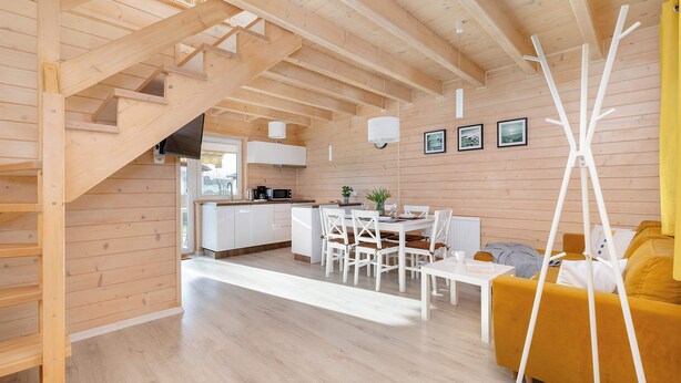 A wooden interior with a staircase, a dining area, and a sofa.