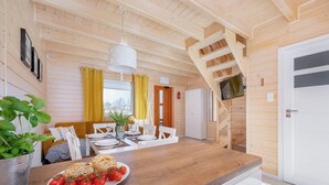 A wooden interior with a dining area, a staircase, and a kitchen.