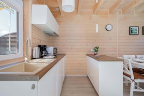 Een kleine keuken met houten wanden, een spoelbak, een koffiezetapparaat en een klok aan de muur.