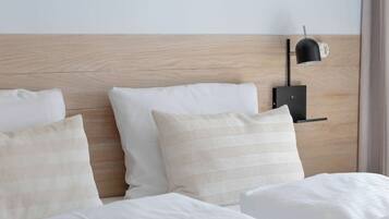 Un lit bien fait, avec du linge de lit blanc et une tête de lit en bois.