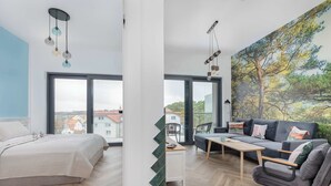 A modern living room with a bed, sofa, and a large window. - Spacious Apartment | Close to the Beach, Parking. (Mrzeżyno)