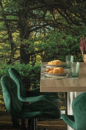 Een eettafel met borden eten en glazen, op de achtergrond bomen.