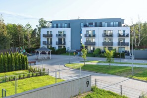A modern apartment building with balconies, a playground, and a well-maintained lawn.
