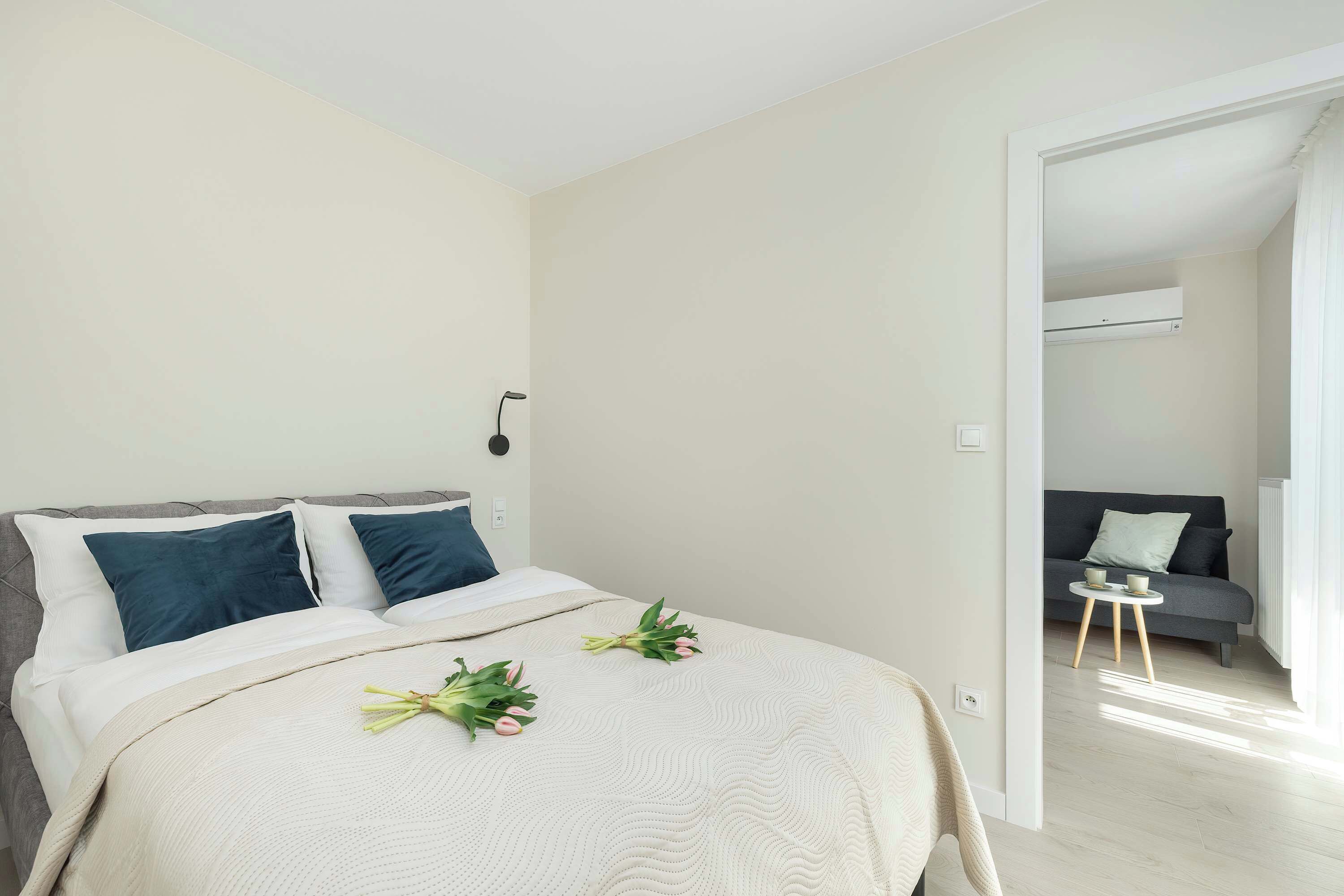 A cozy bedroom with a double bed, bedside tables, and natural light. The decor is simple yet elegant.