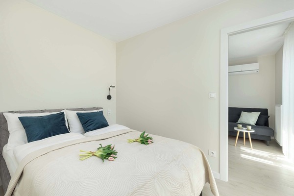 A cozy bedroom with a double bed, bedside tables, and natural light. The decor is simple yet elegant.