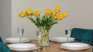 A dining table with white plates, cutlery, and a vase of yellow tulips.