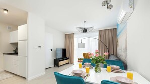 Un coin repas moderne avec une table blanche dressée pour quatre personnes, des chaises de couleur turquoise et un vase rempli de fleurs.