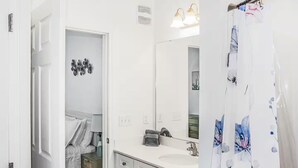 Ein modernes Badezimmer mit einem großen Spiegel, einem Waschbecken und einer Duschvorhang.