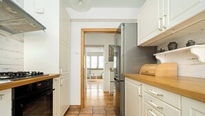 Eine Küche mit weißen Schränken, einer Holz Arbeitsplatte, einem Edelstahl-Kühlschrank und einem schwarzen Backofen.