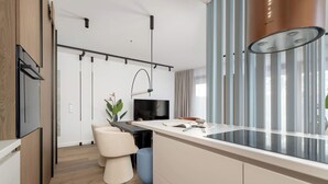 A modern kitchen with a central island, a built-in TV, and a pendant light.