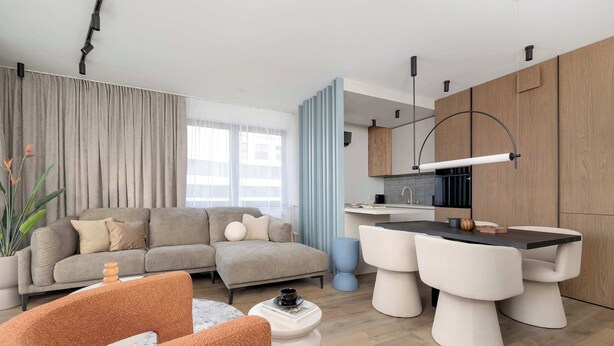 A modern living room with a sofa, coffee table, and dining area.