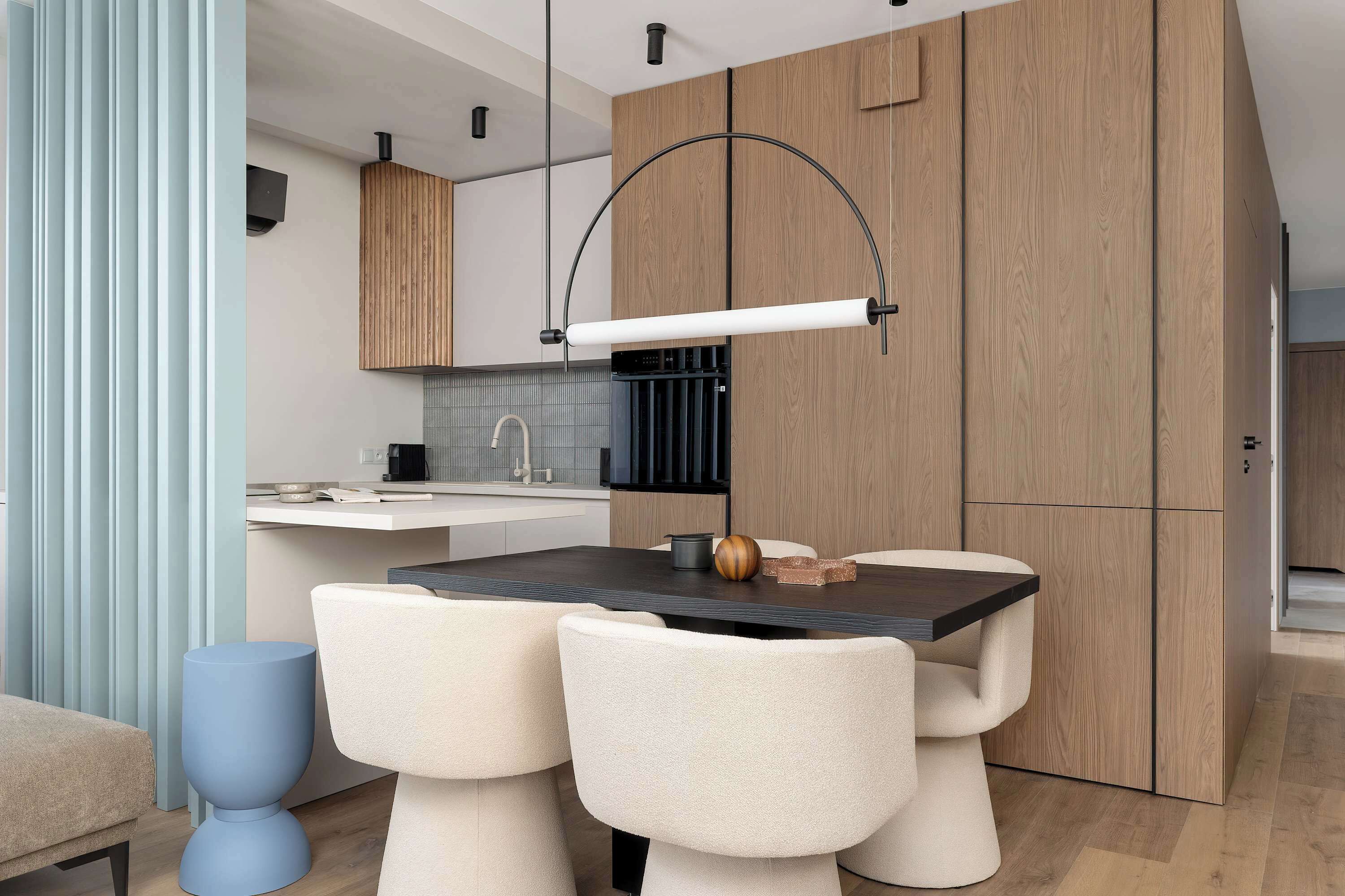 Une cuisine moderne dotée d’un îlot central, de meubles en bois et d’un luminaire suspendu.