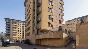 A multi-story residential building with balconies, a staircase, and a gated entrance.