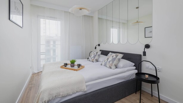 A modern bedroom with a large bed, bedside tables, and a large mirror.