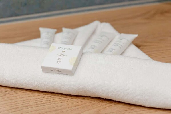 A white towel with a box of Arnismes The Tonique Savon on it, placed on a wooden surface.
