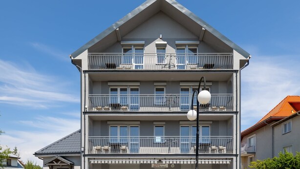 Een meerhoog gebouw met balkons, een heldere lucht en een straatverlichting.