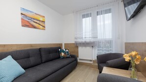 Een moderne woonkamer met een bank, fauteuil en een schilderij aan de muur.