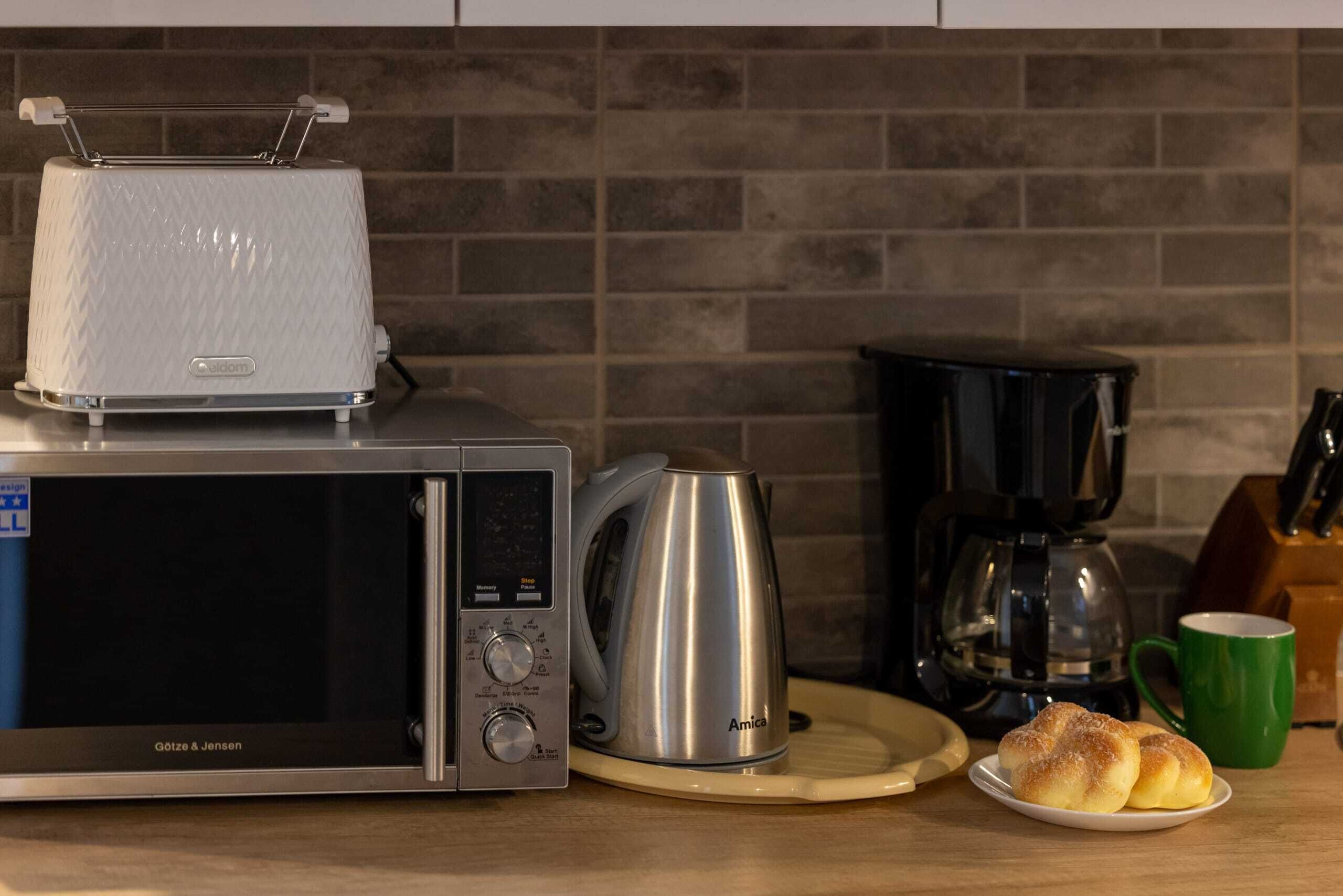 A kitchen with a toaster, a coffee maker, and a plate of bread.