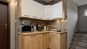 A modern kitchen with white cabinets, a microwave, coffee maker, and a knife block.
