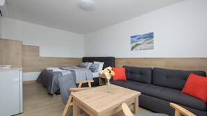 A room with a bed, a sofa, a table, and a small desk.