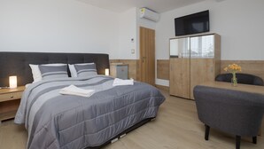 A modern bedroom with a bed, bedside table, wardrobe, and a TV mounted on the wall.