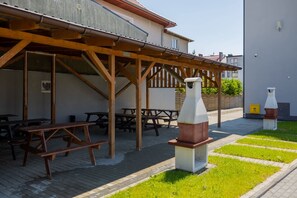 A covered outdoor area with picnic tables and a barbecue grill.