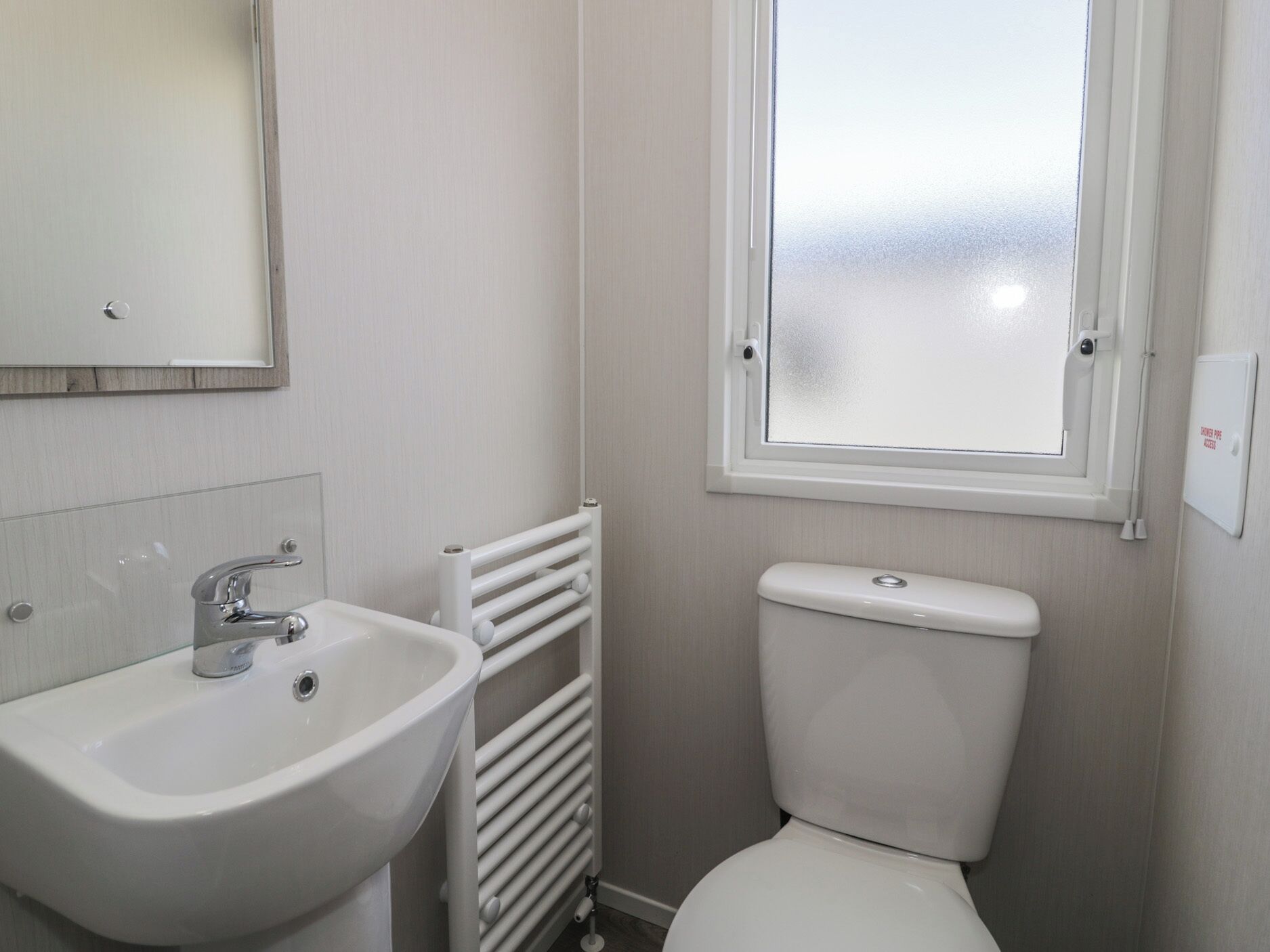 A bathroom with a white sink, a toilet, a radiator, and a window.