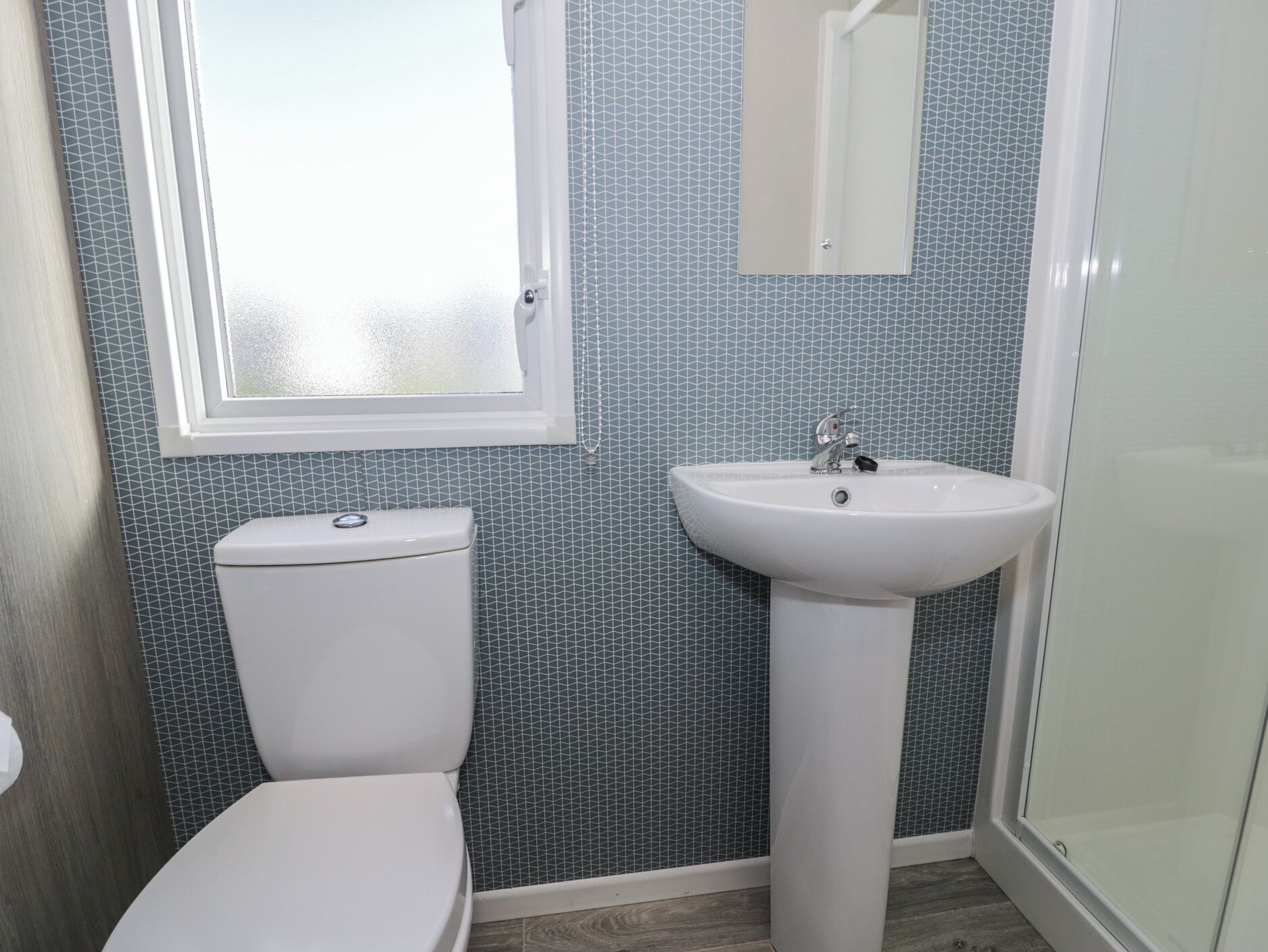 Un baño con inodoro, lavamanos y ventana.