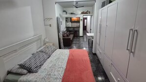 Een compacte hotelkamer met een bed, een kledingkast, een klein kitchenette en een badkamer.