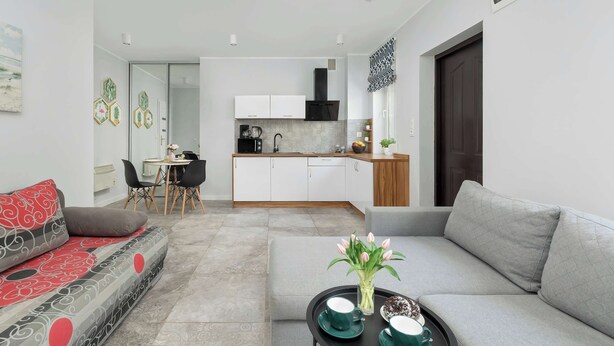 Una sala de estar moderna con un sofá, una mesa de centro con un florero, y un comedor con sillas y una mesa.