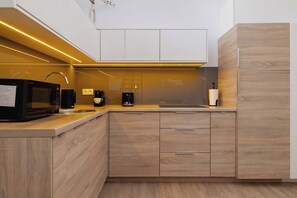 A modern kitchen with a microwave, coffee maker, and wooden cabinets.