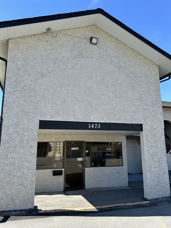 A building with a white exterior and a black roof. The address number 1473 is visible above the entrance. - Lakecity Inn (Penticton)
