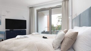 Une chambre d’hôtel moderne dotée d’un grand lit, d’une télévision à écran plat et d’un balcon offrant une vue sur la ville.