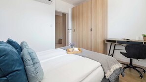 A modern bedroom with a bed, bedside table, and a desk with a chair.